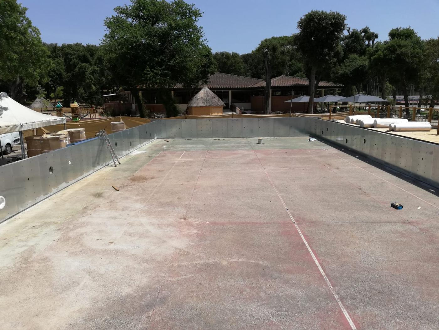 Costruzione di una piscina fuori terra in acciaio su un campo da tennis
